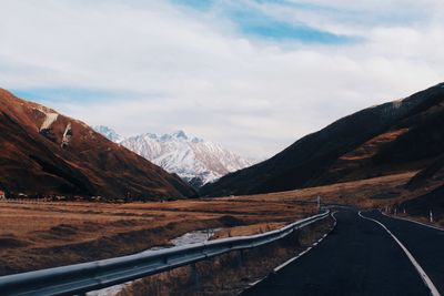 Scenic view of road by mountains against sky