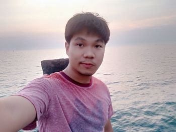 Portrait of boy at beach against sky during sunset