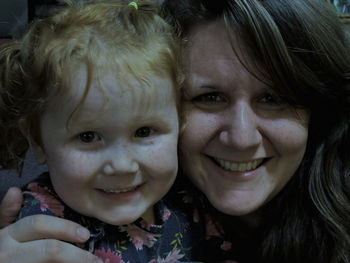 Portrait of smiling mother and daughter at home