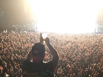 Rear view of people enjoying music concert against sky