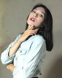 Beautiful young woman looking away against wall