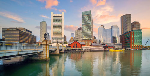 Bridge over river by buildings against sky in city