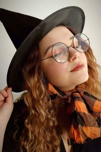 Close-up of young woman wearing witch costume against wall