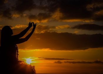 Silhouette woman against orange sky during sunset