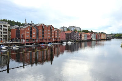 Buildings by river against sky