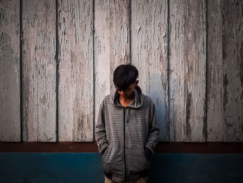 Full length of woman standing against wooden wall