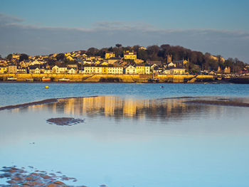Scenic view of sea by townscape against sky