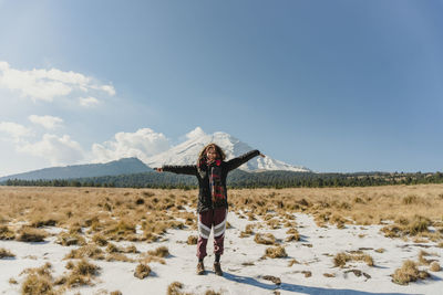 Portrait of happy woman standing on field against sky