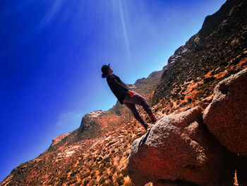 Low angle view of rock on mountain against blue sky