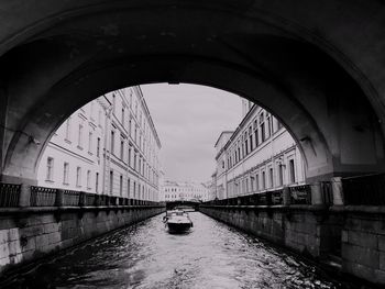 Arch bridge over canal amidst buildings against sky