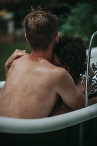 Rear view of shirtless man and woman in bathroom