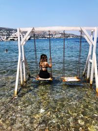 Woman sitting in sea against sky