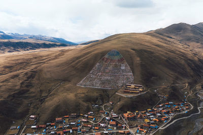 Aerial view of buildings by mountains against cloudy sky