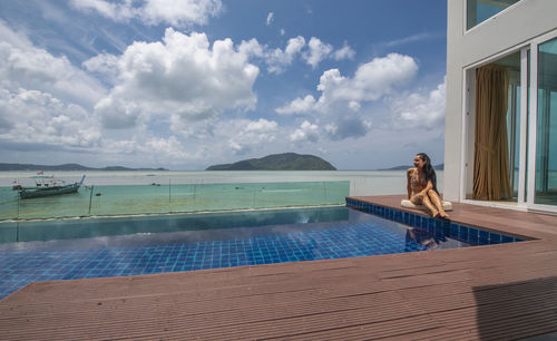 Beautiful woman sitting by the pool at luxury villa in phuket