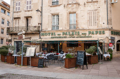 Chairs and tables at sidewalk cafe against buildings in city