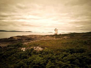 Lighthouse amidst sea and buildings against sky