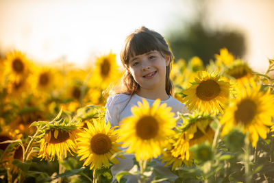 Portrait of girl with yellow flowers on field
