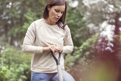 Mid adult woman holding gardening fork at organic farm