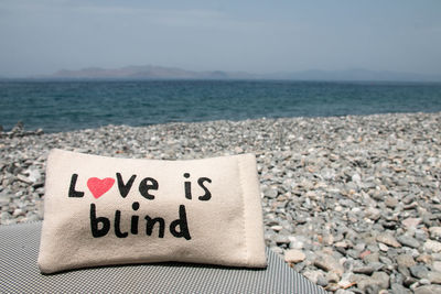 Text on rock at beach against sky