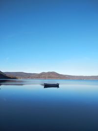 Scenic view of lake against clear blue sky