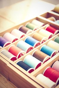 High angle view of multi colored spools in wooden box