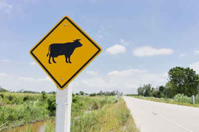 Road sign on land against sky