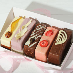 Set of various mini cakes in a box with festive decor unboxed. glazed with chocolate
 and icing 