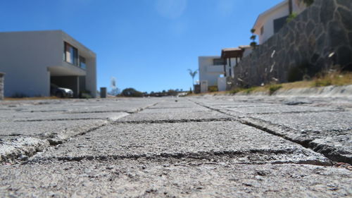 Surface level of road by buildings against blue sky