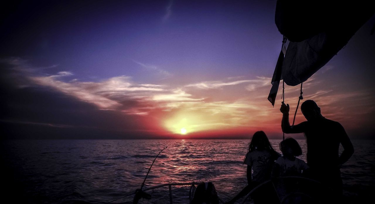 SILHOUETTE PEOPLE ON SEA AGAINST SKY DURING SUNSET