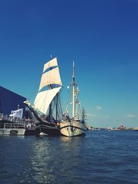 Sailboat sailing in sea against clear blue sky