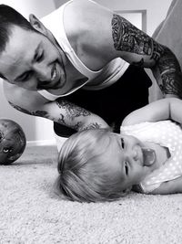 Cheerful father and daughter playing on rug at home