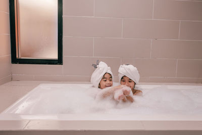 Two daughters with bubbles in bathtub