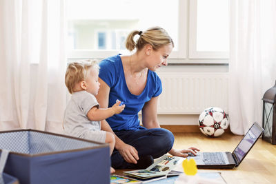 Baby boy with mother using laptop at home