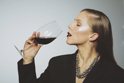 Close-up of a woman drinking glass against white background