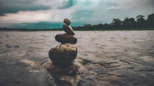 Stack of stones on beach against sky