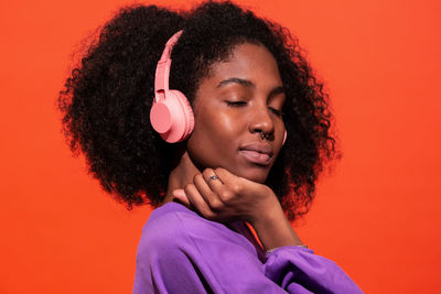 Portrait of a beautiful young woman against orange background