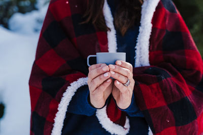 Midsection of woman holding coffee cup during winter