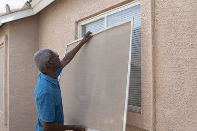 Man installing window frame of house