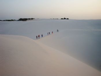 People on snow covered land against sky