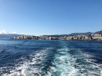 Scenic view of sea by buildings against blue sky