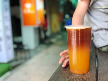 Midsection of woman holding drink in glass on table