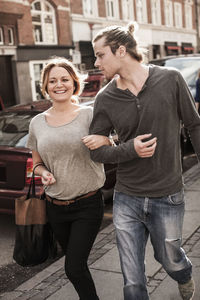 Happy couple with arm in arm walking on sidewalk