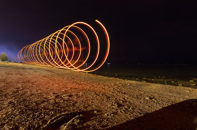 Light trails at beach against sky at night