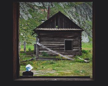 Rear view of man sitting on window of building