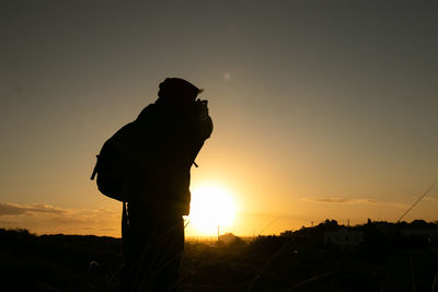 Rear view of silhouette man standing against sky during sunset