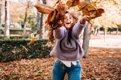 Midsection of person standing on tree during autumn