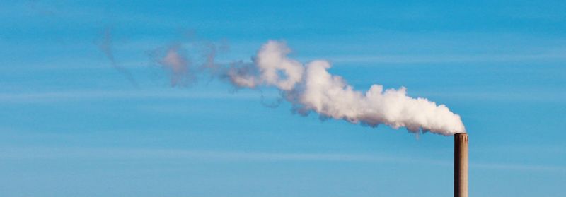 Smoke emitting from chimney against sky