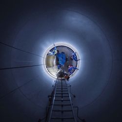 Low angle view of workers in illuminated wind turbine at night