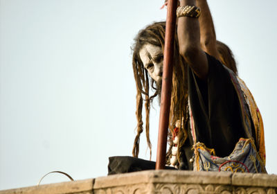 Low angle portrait of woman against clear sky