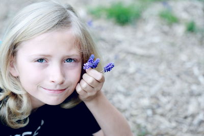 Close-up portrait of a girl holding purple flower